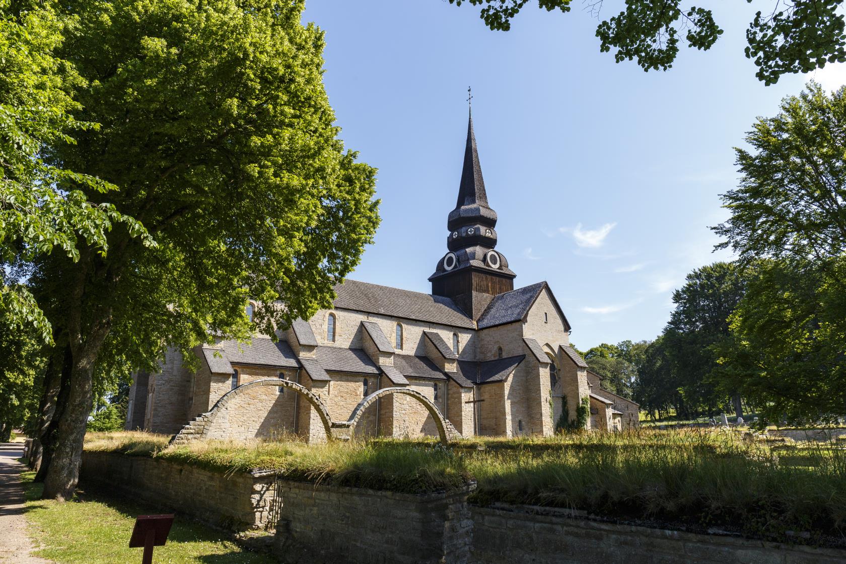 En kyrka i sommarsol. Grönskande träd runt om.