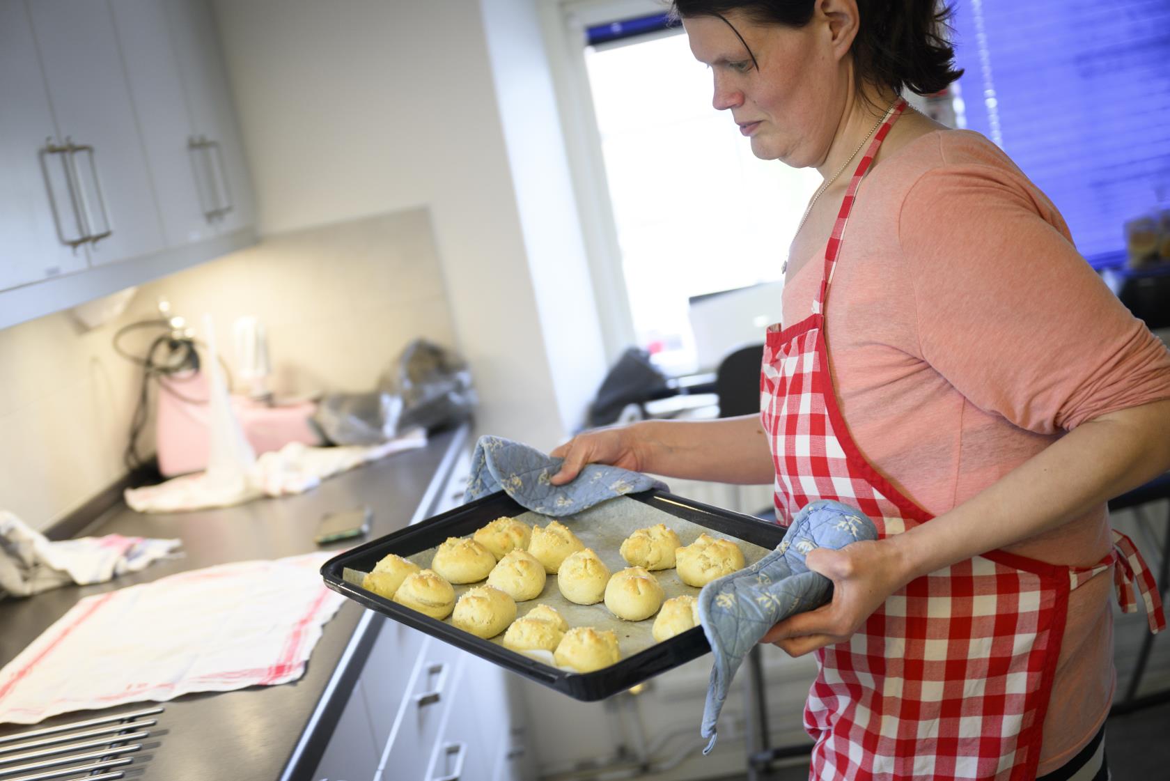 En kvinna har just tagit ut en plåt med nygräddade bullar.