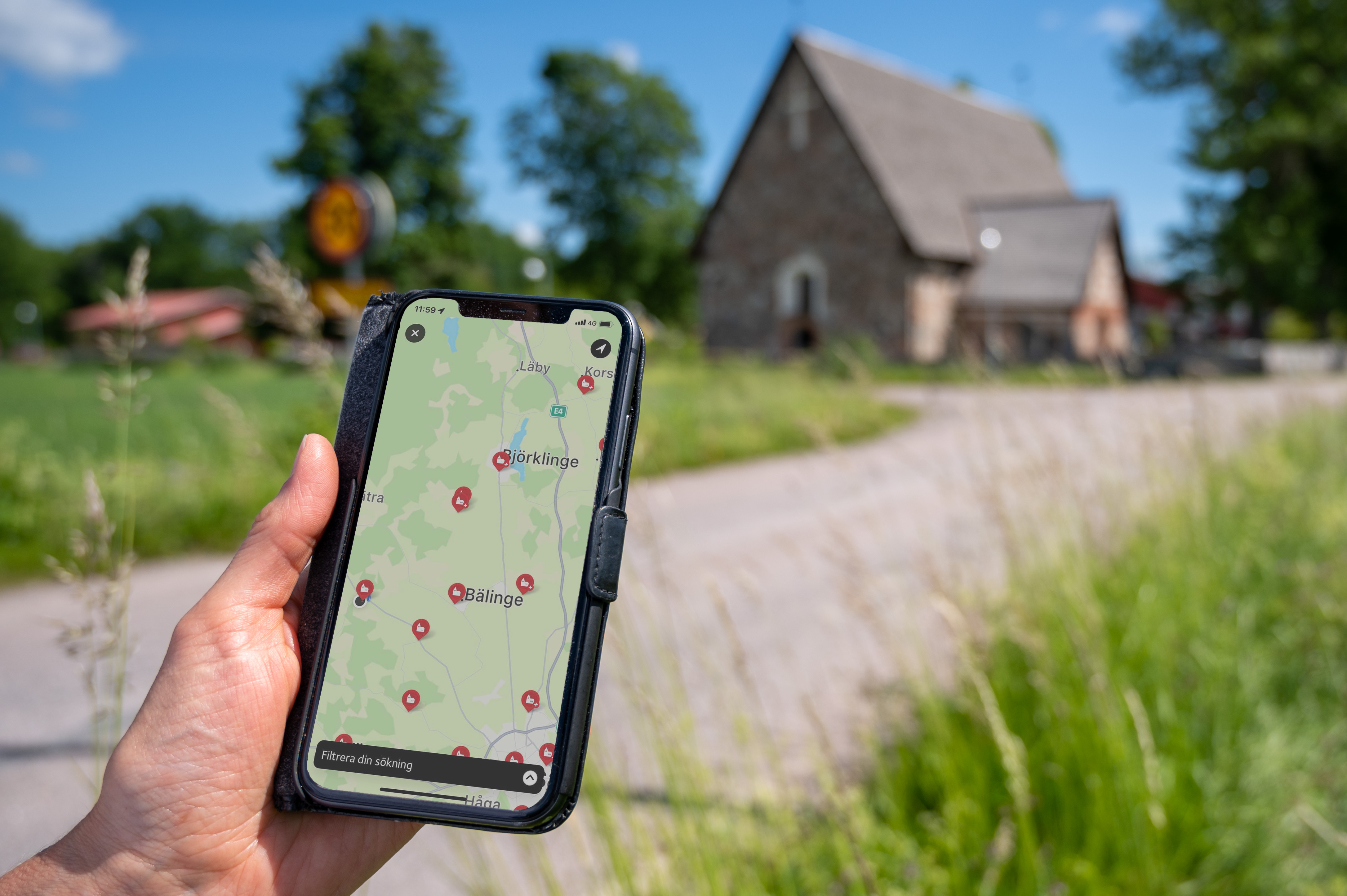 En person som kommit fram till en gammal kyrka håller en mobiltelefon i handen. På skärmen visas kyrkans position på en karta.