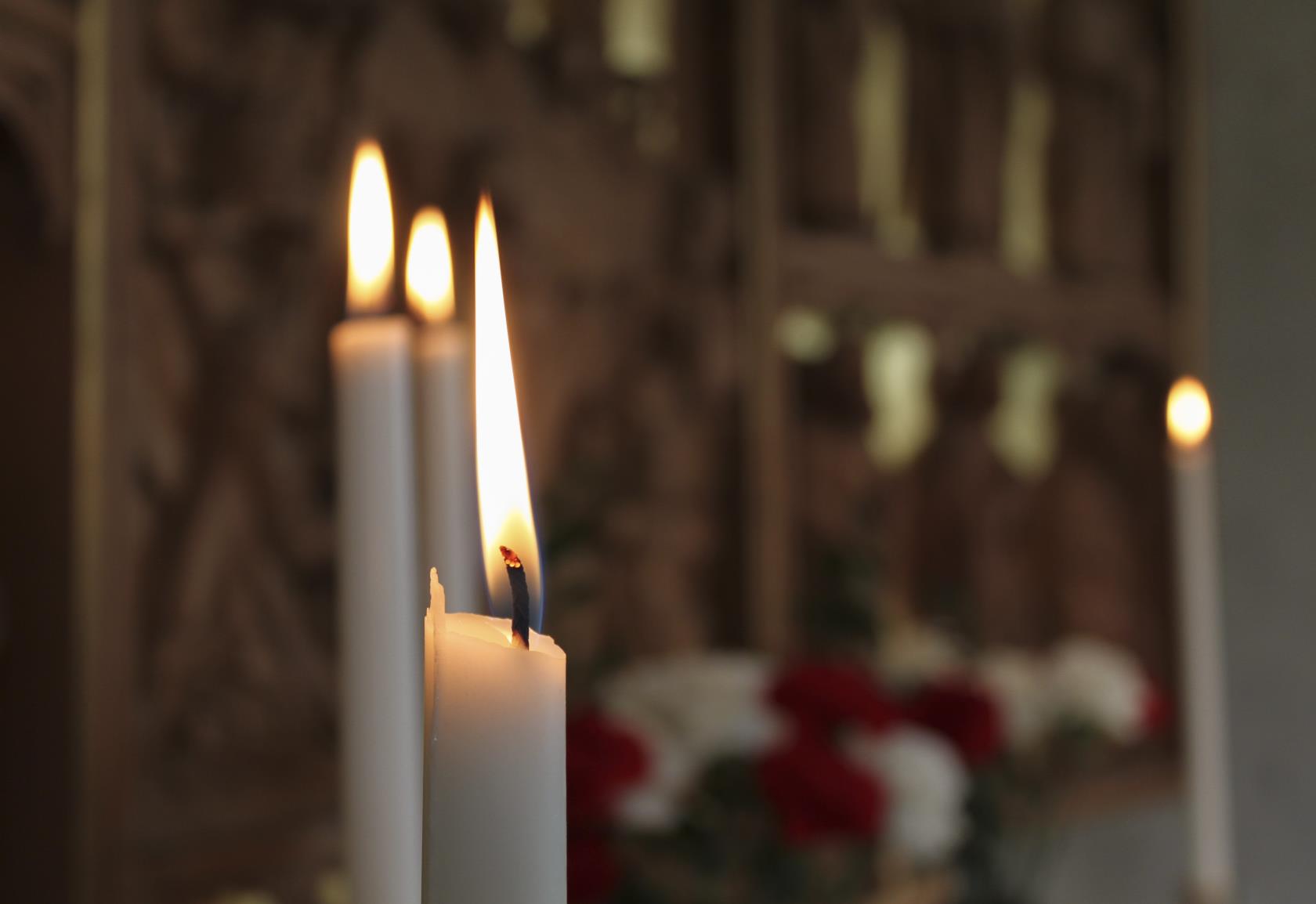 Närbild på brinnande stearinljus i en kyrka.