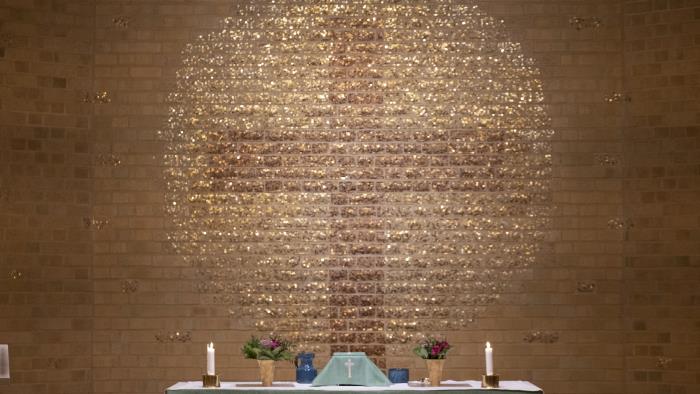Ett stort kors målat på väggen bakom ett altare.