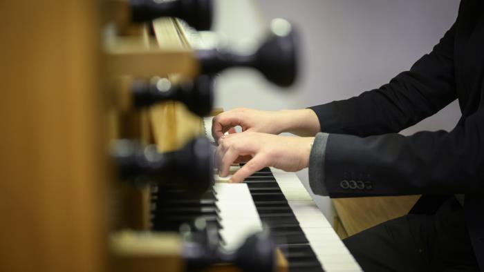 Någon i svart kavaj spelar orgel.