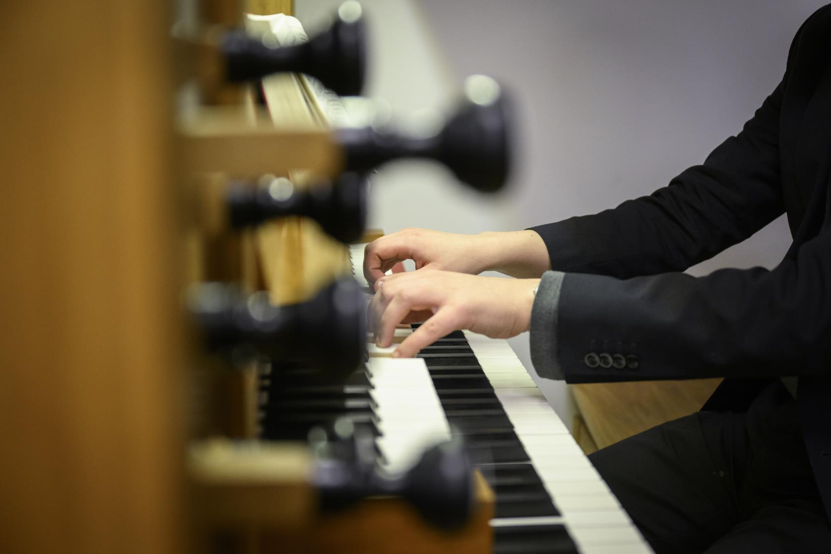 Någon i svart kavaj spelar orgel.