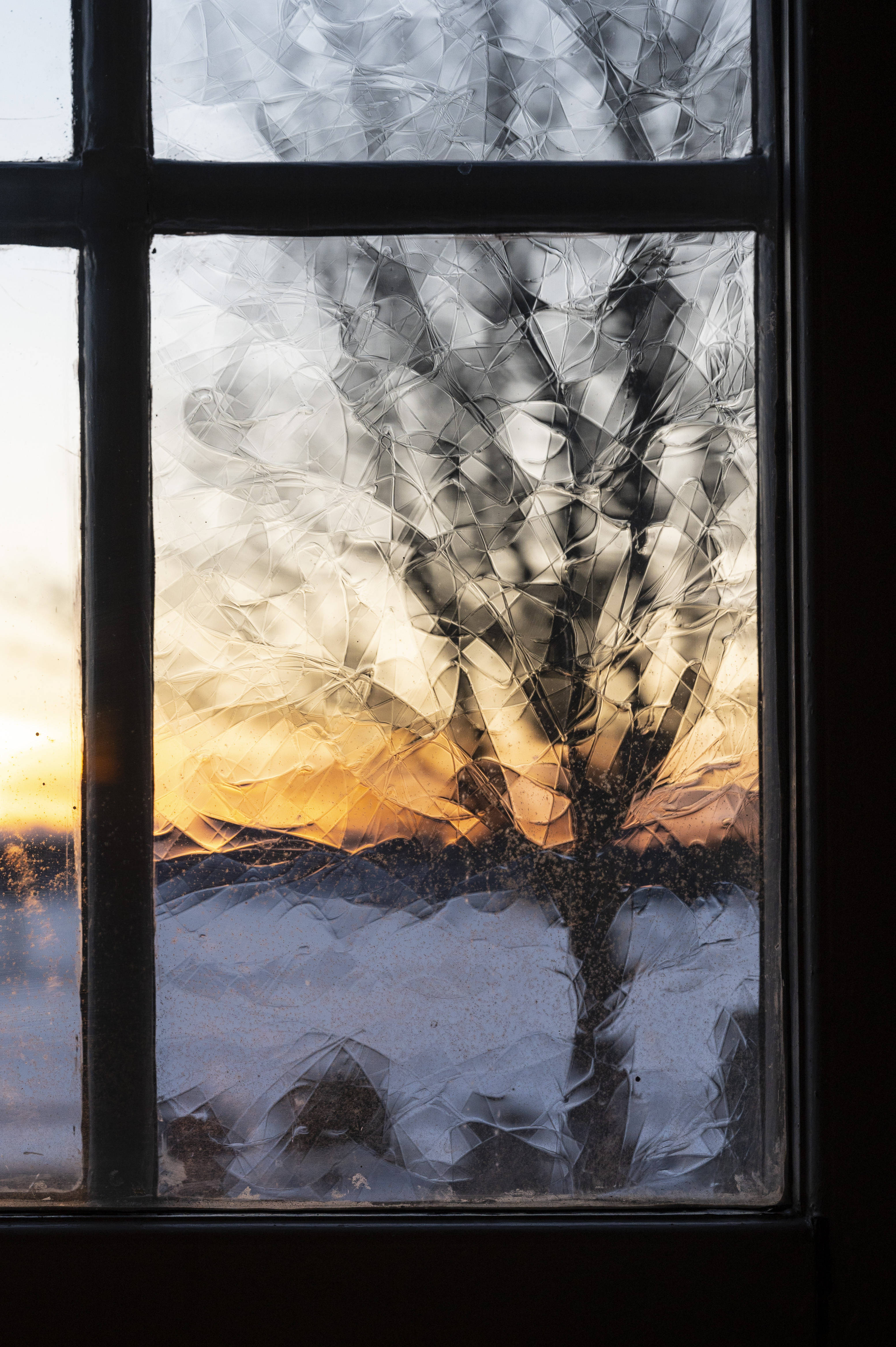 Solnedgången syns genom ett fönster av munblåst glas.