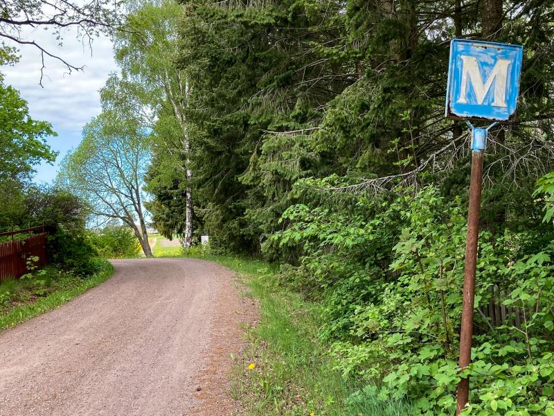 En grusväg i skogen och en gammal vägskylt för mötesplats.