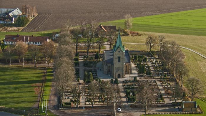 Ljus tegelkyrka med tre korsarmar och trappstensgavlar.