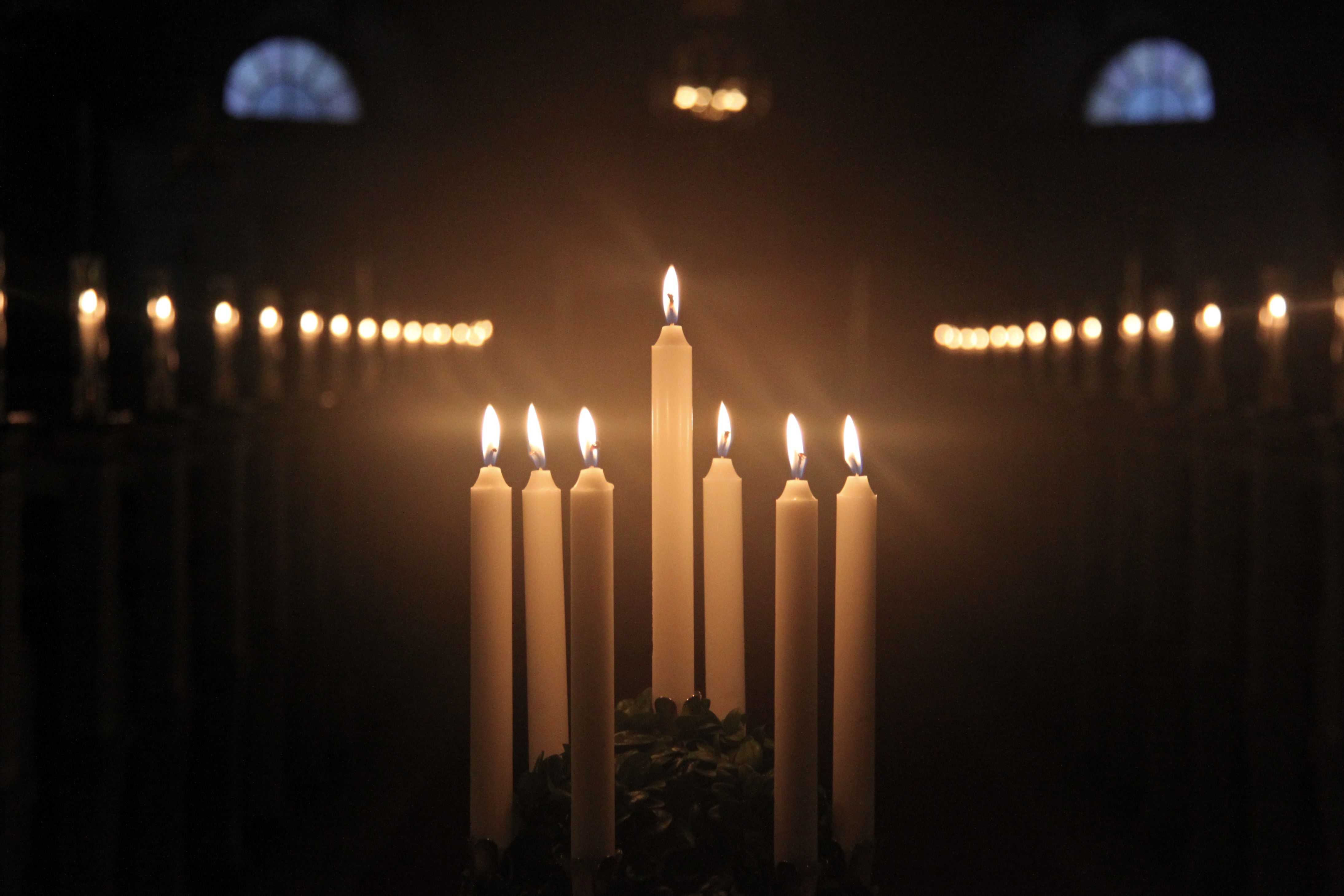 En luciakrona med brinnande ljus i en mörk kyrka.