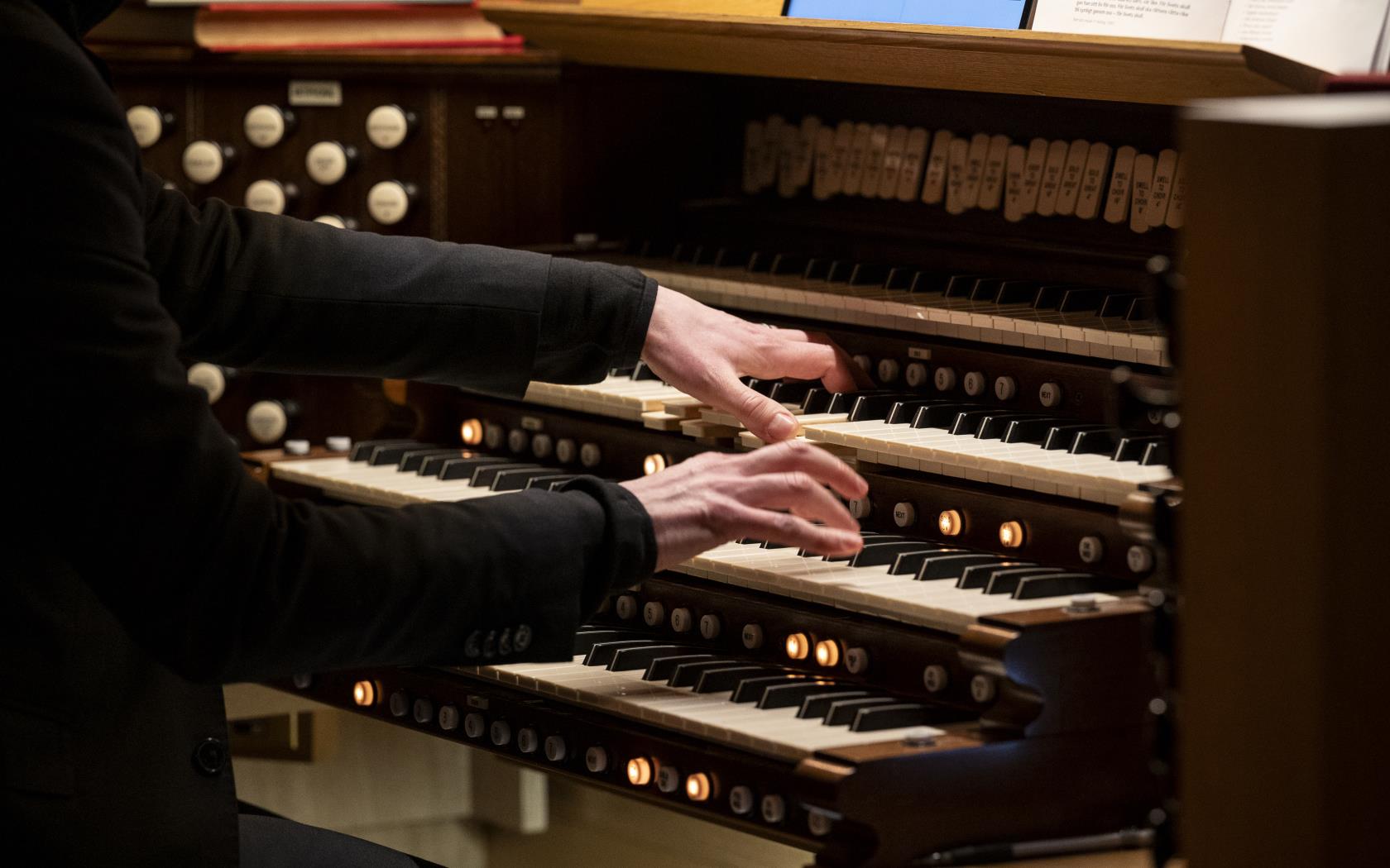 Någon spelar orgel med händerna på olika klaviaturrader.