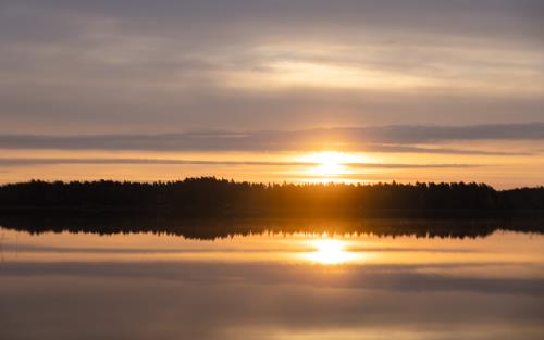 En solnedgång speglas i sjöns vattenyta.