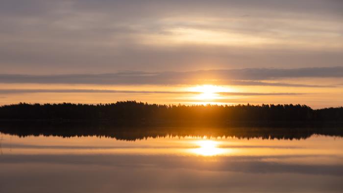 En solnedgång speglas i sjöns vattenyta.