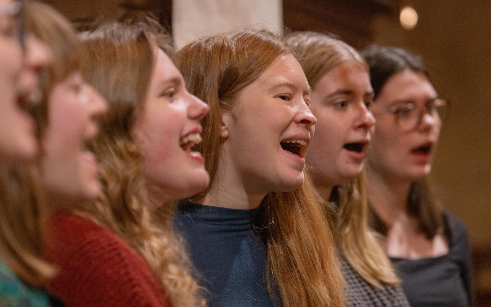 En blandad kör övar i en kyrka.