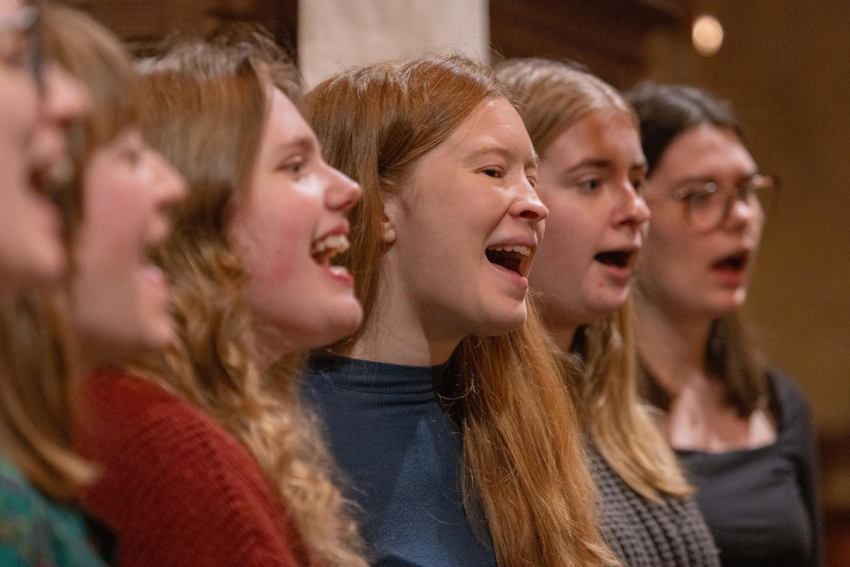 En blandad kör övar i en kyrka.