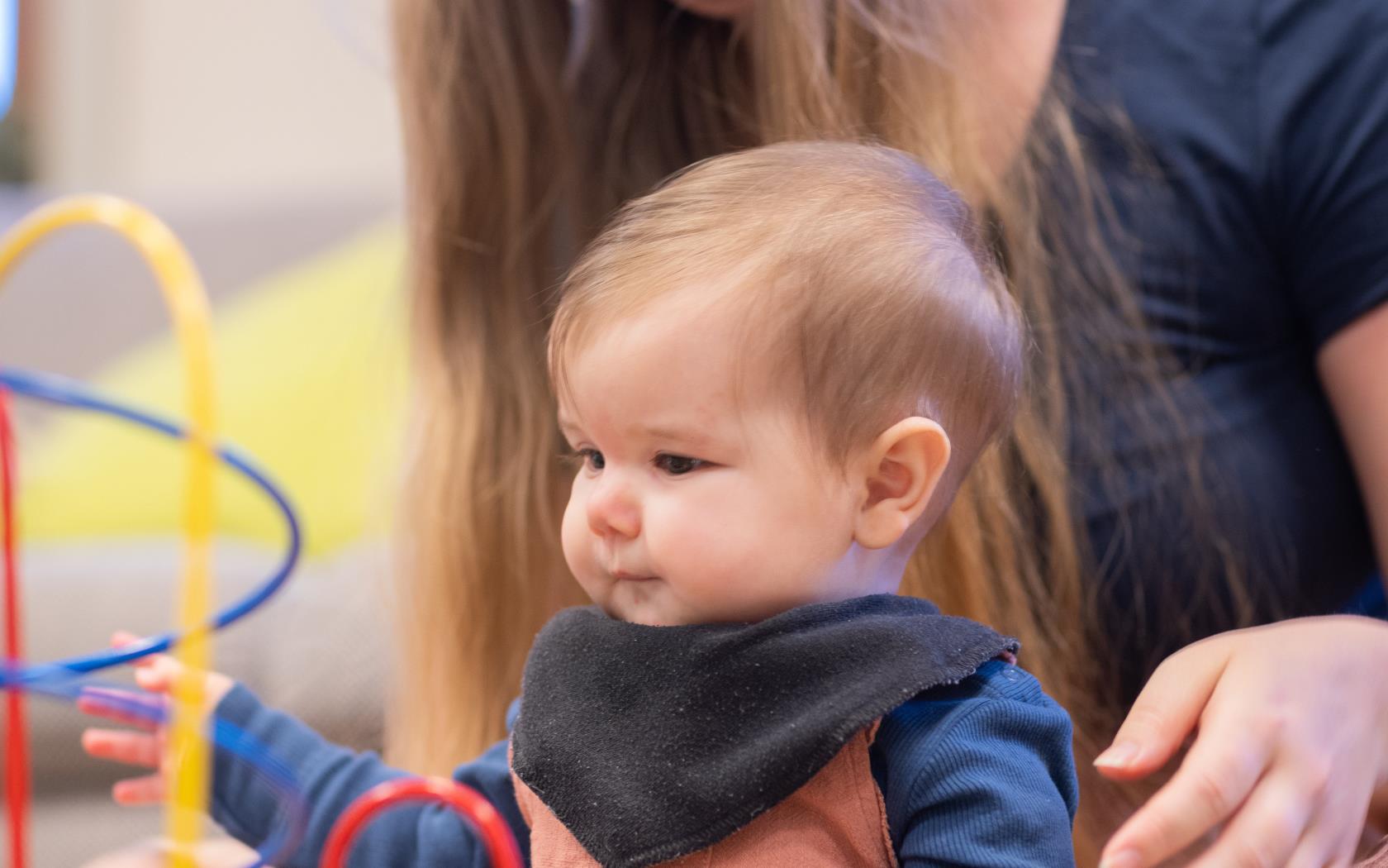 En kvinna sitter på golvet och leker med sin bebis.