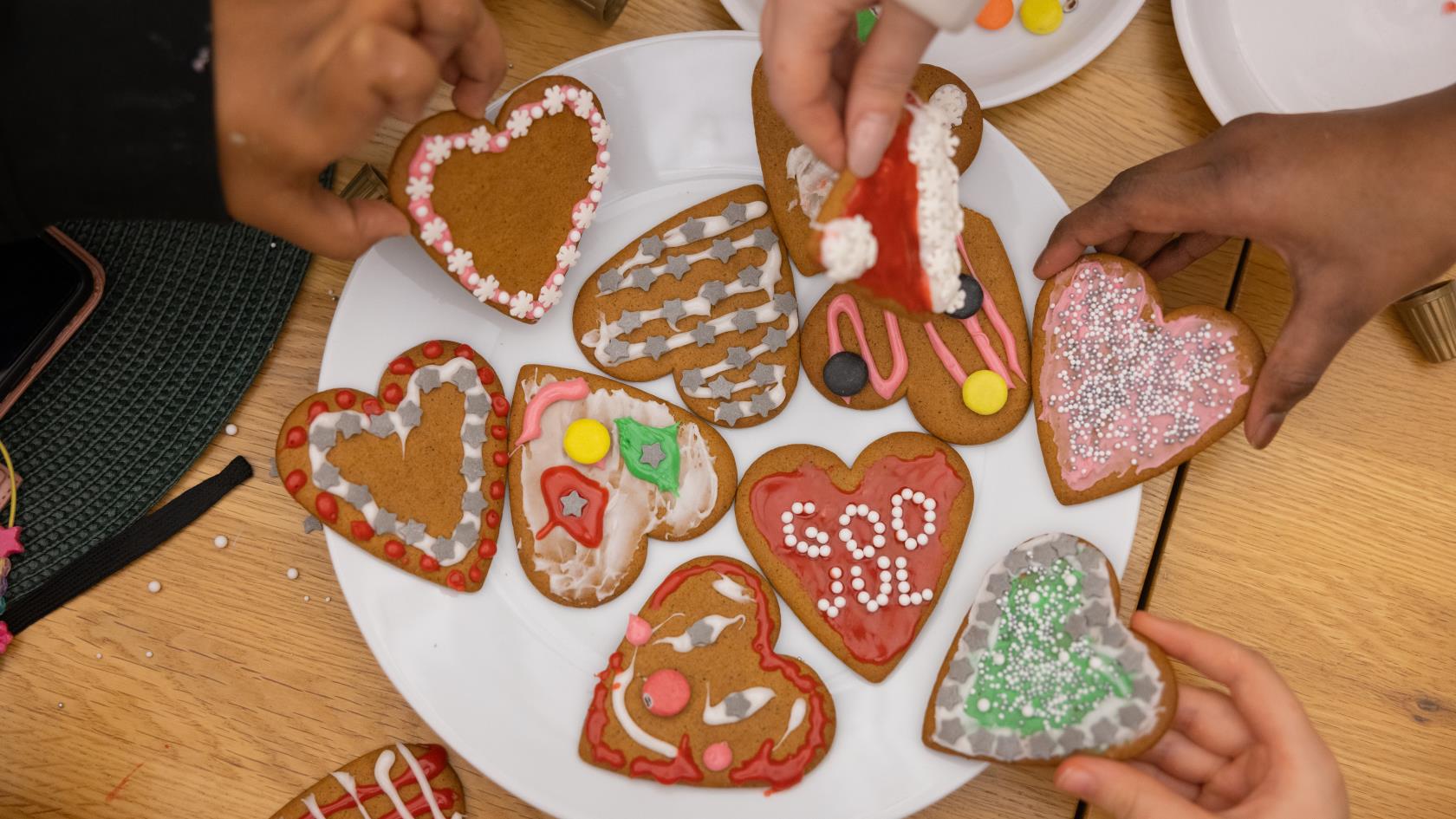 En tallrik med garnerade pepparkakshjärtan och barnhänder som lägger dit dem.