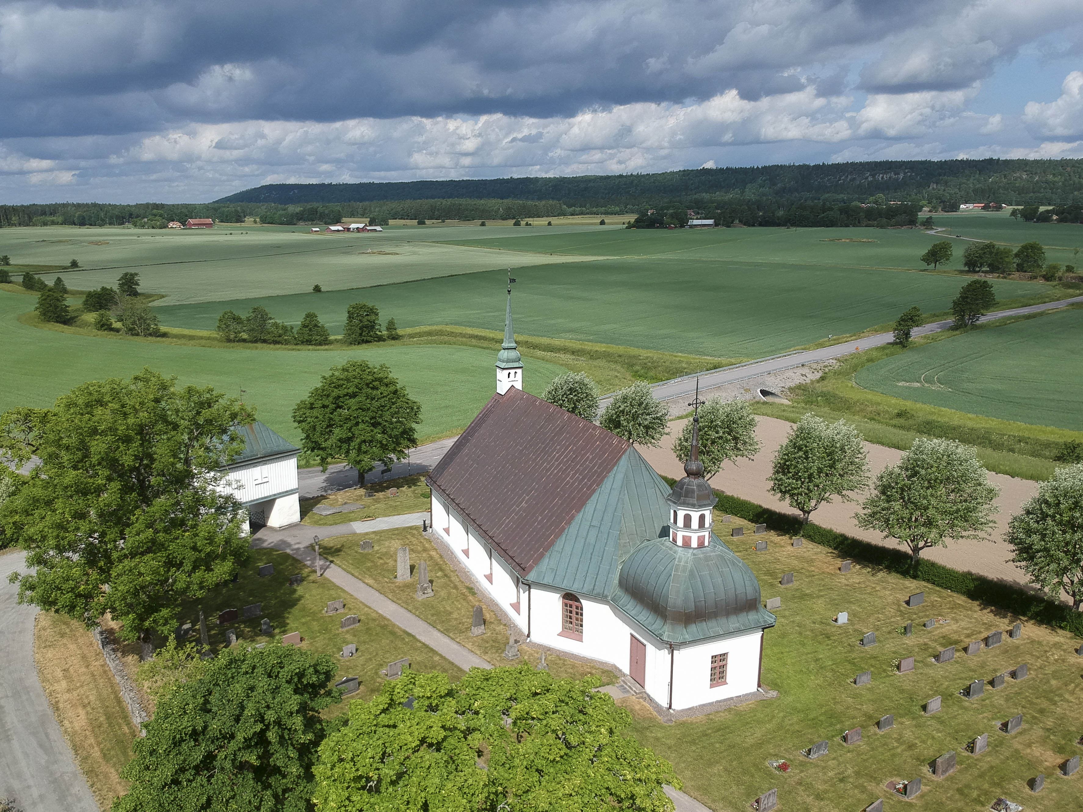 Flygfoto vit kyrka i landsbygd, sommar. 