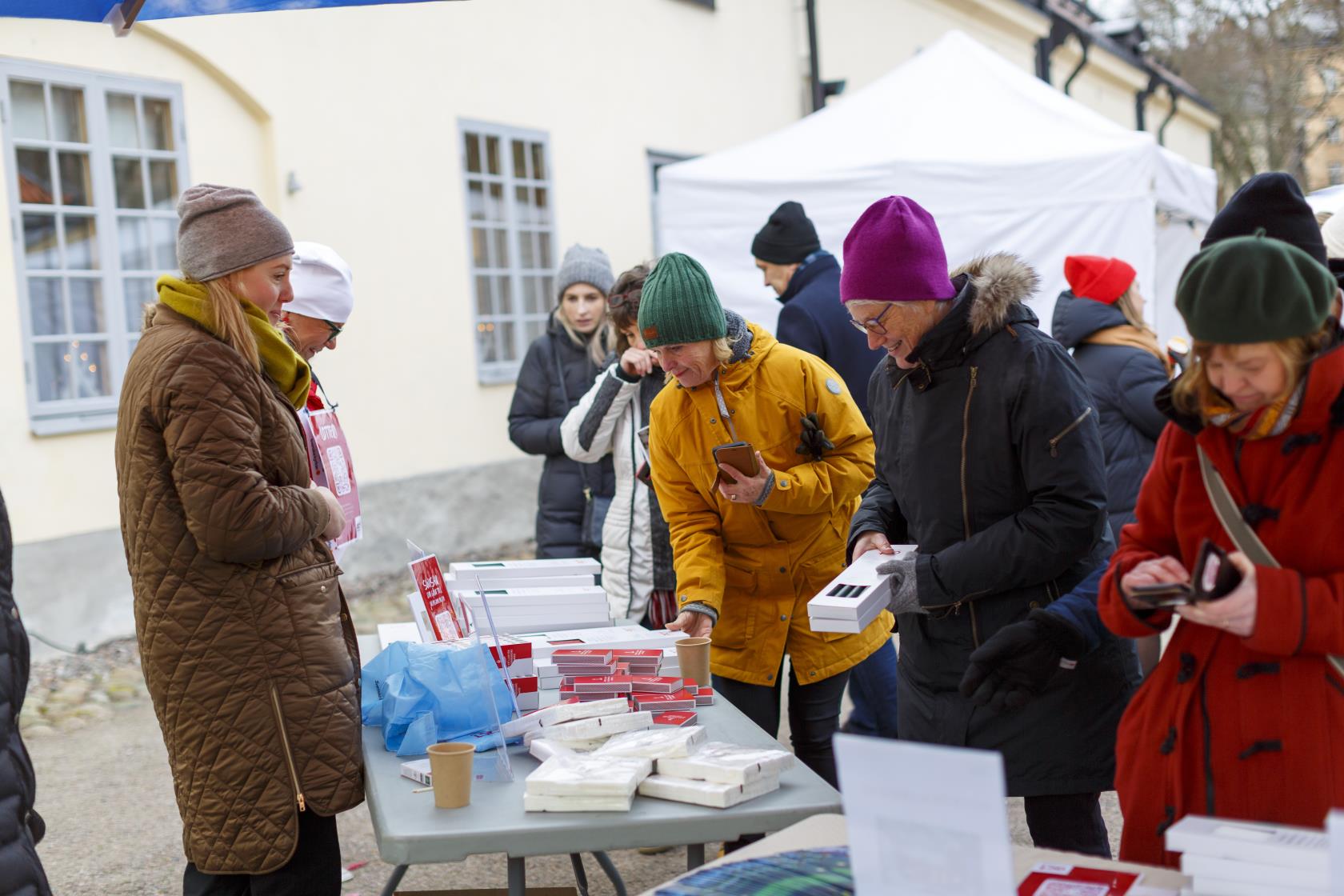 Arbetare från Act Svenska kyrkan står utomhus och säljer ljus och tändstickor.