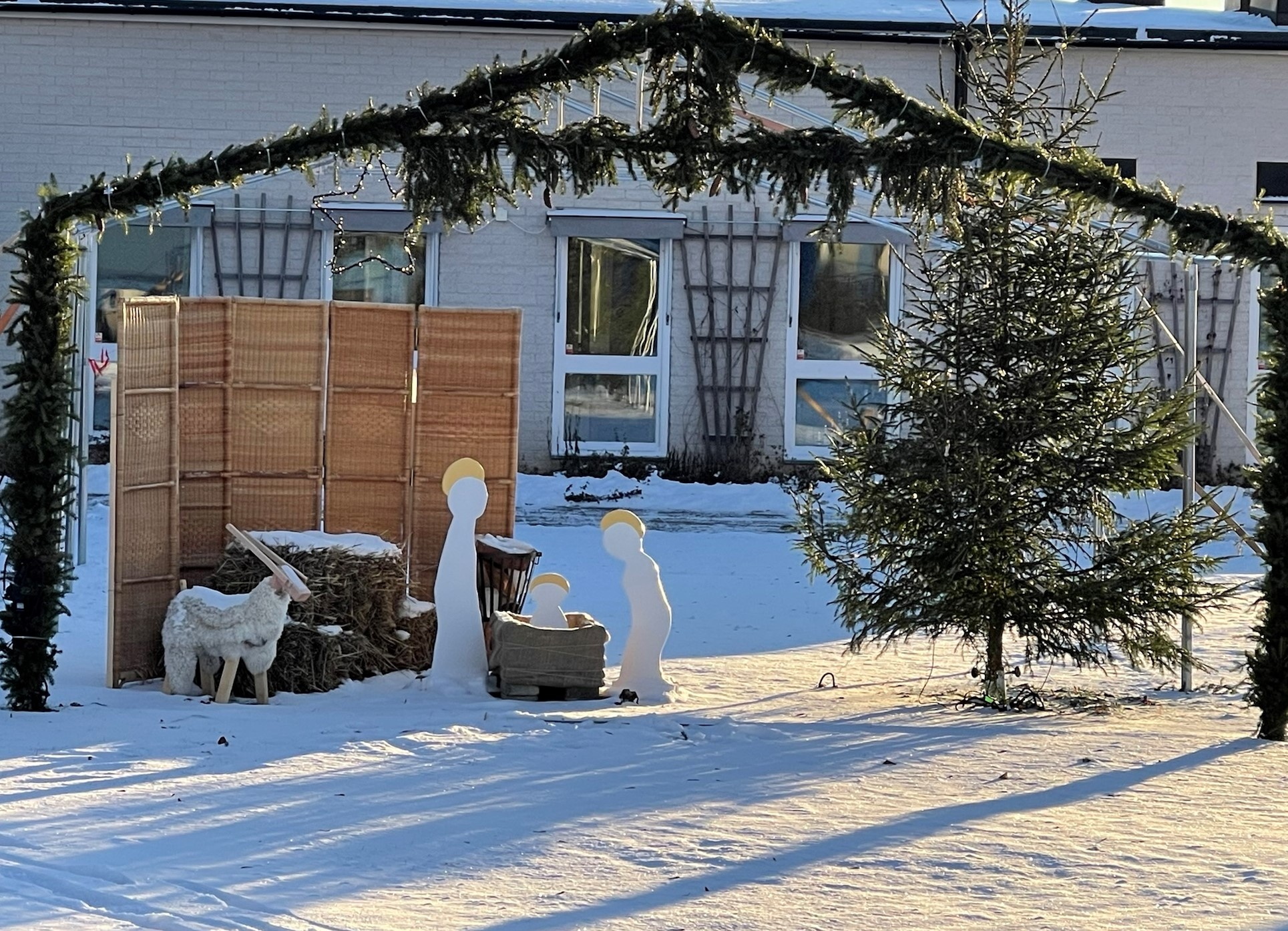 Julkrubba utomhus med snö på marken.