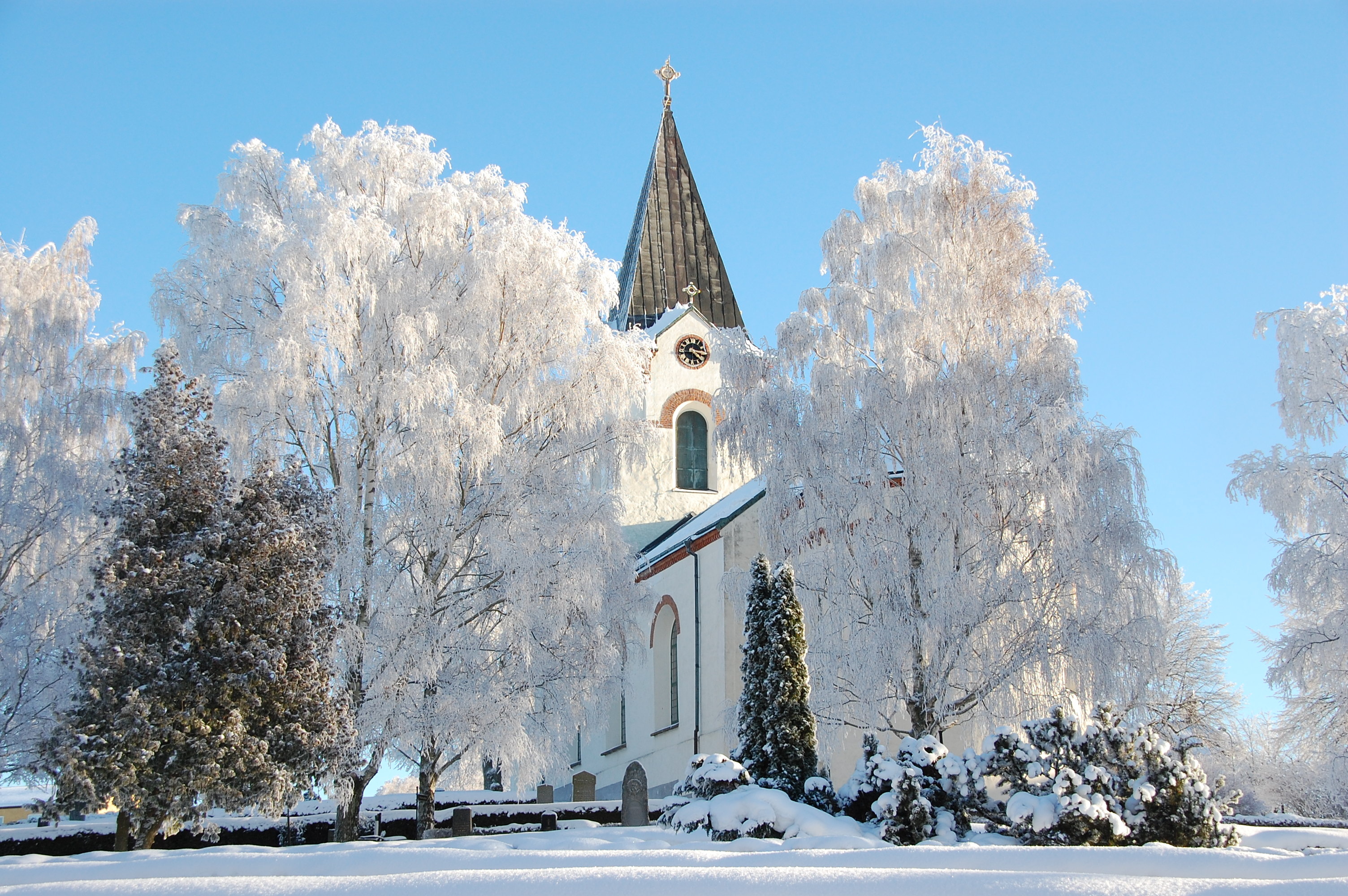 Ödeshögs kyrka i vinterskrud med rimfrost i träden runt kyrkan.