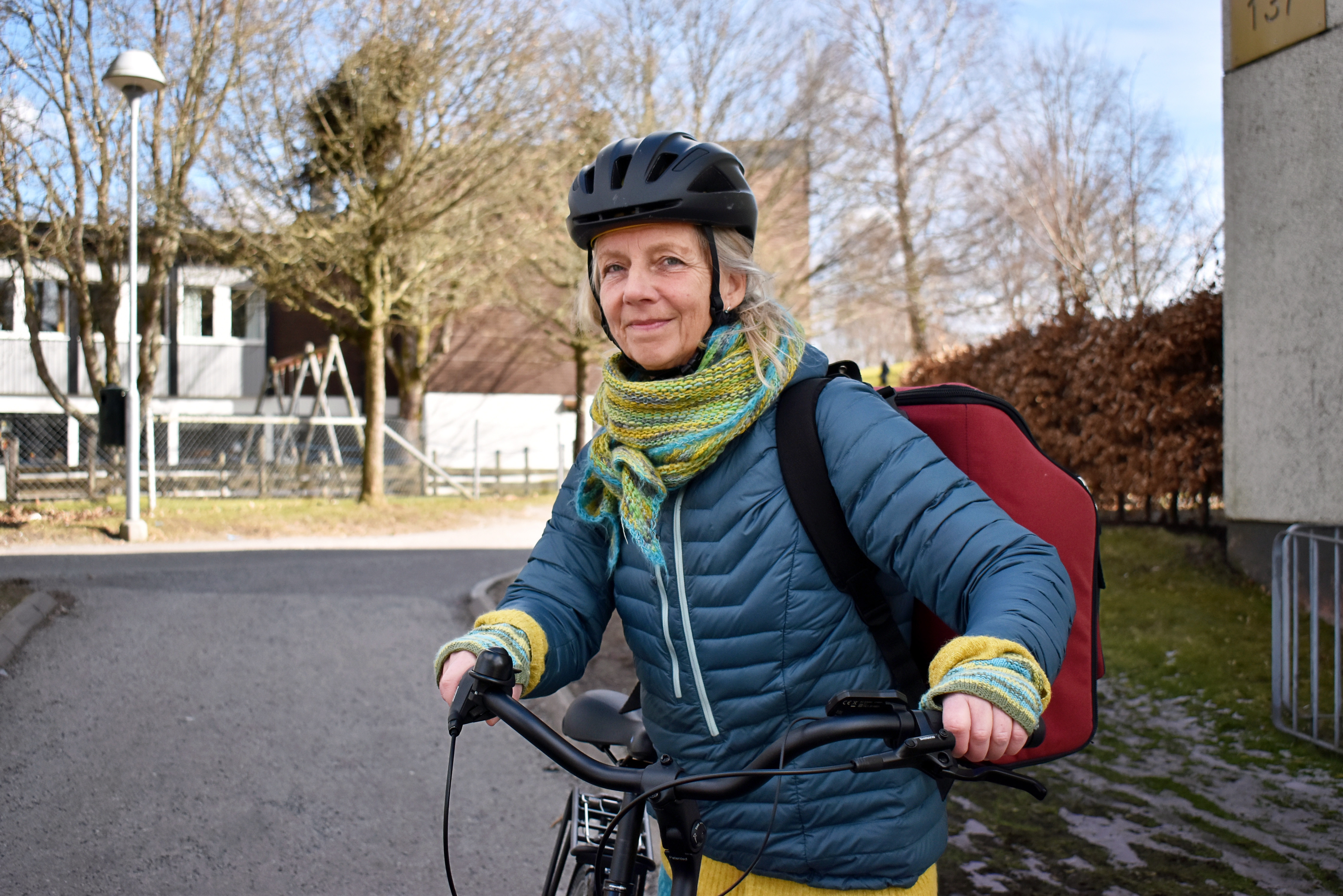 Kvinna på cykel. Hon har cykelhjälm och ryggsäck.