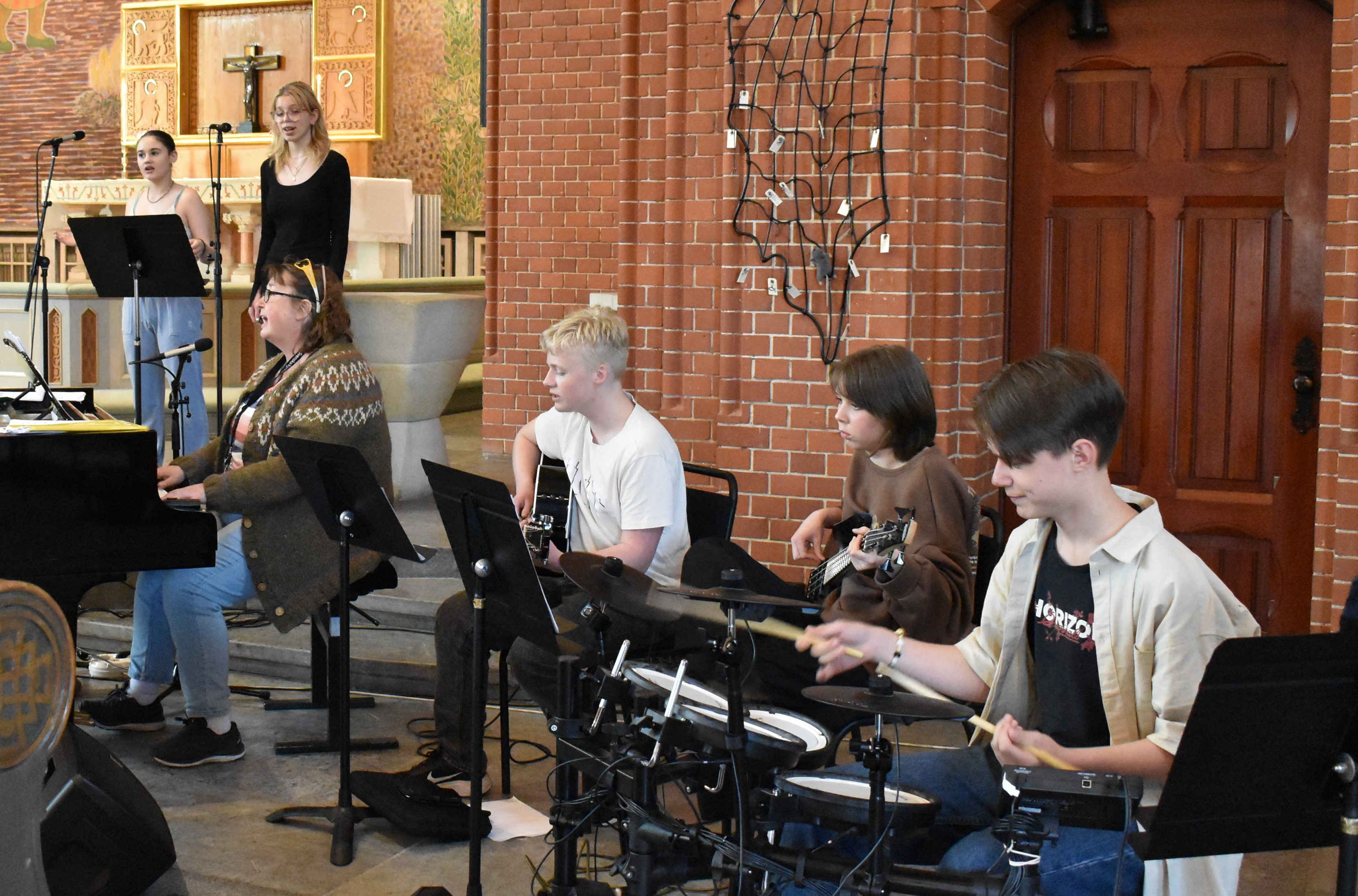 Tre ungdomar med musikinstrument i kyrka.