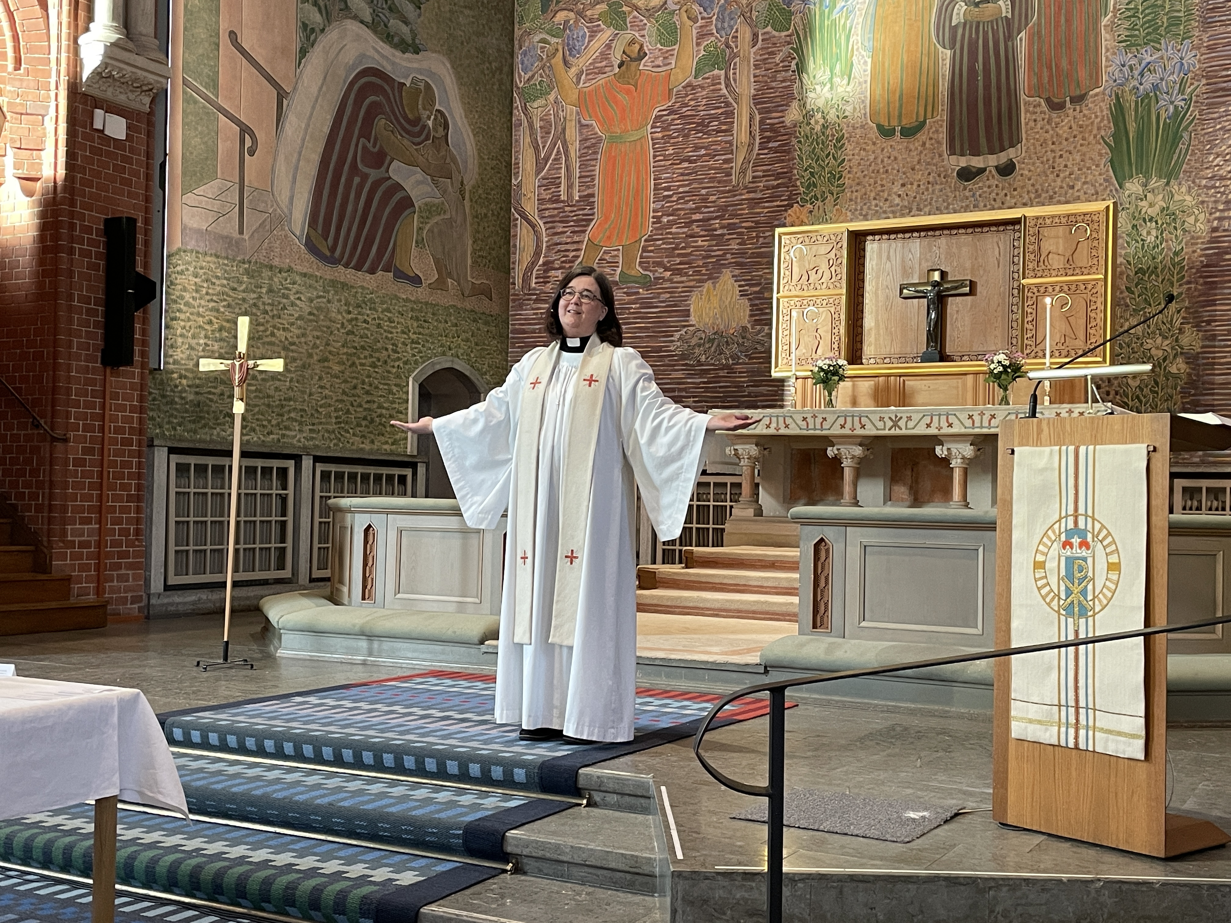 Präst framför altaret i kyrka.