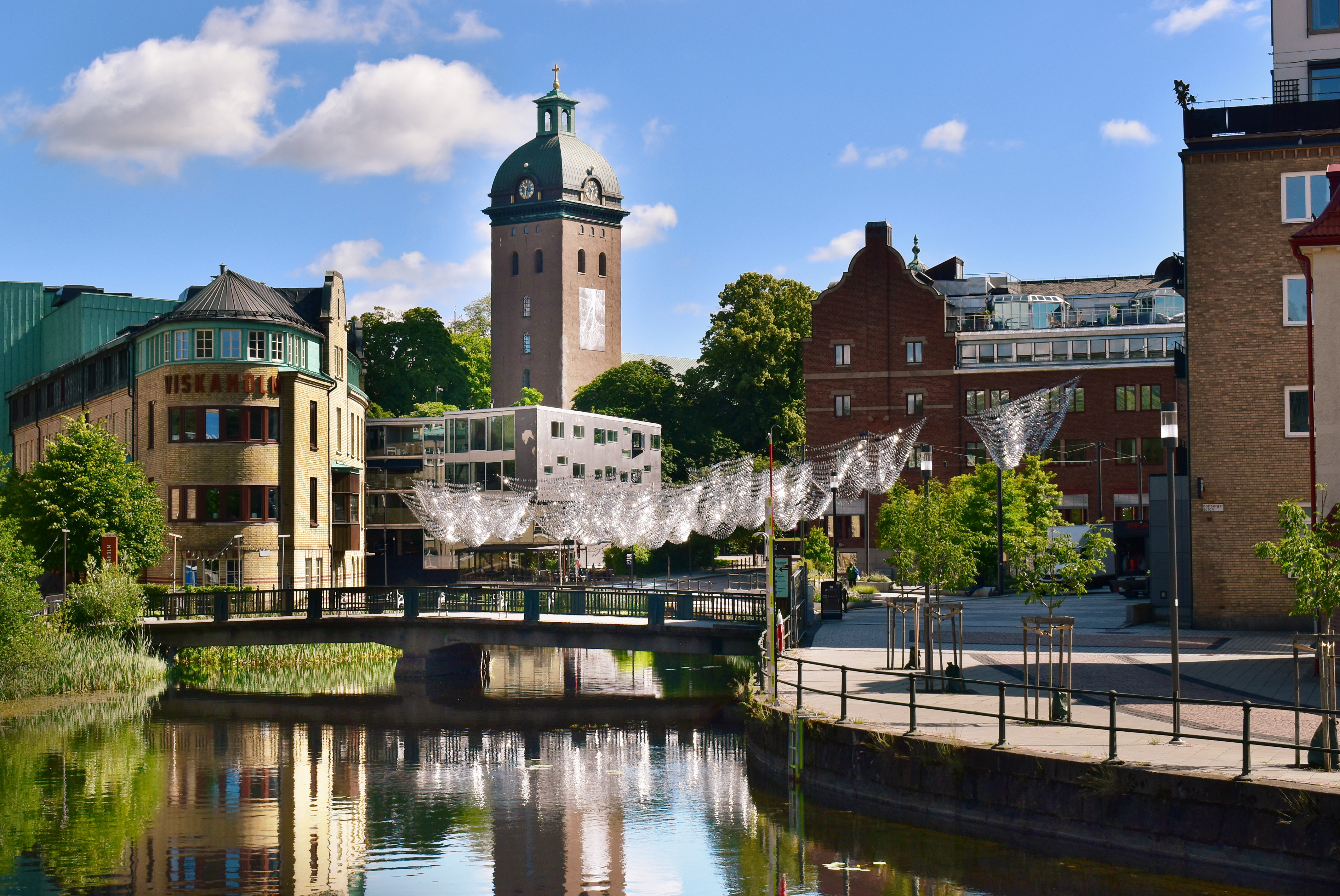 Kryka i stadslandskap med vattendrag i förgrunden.