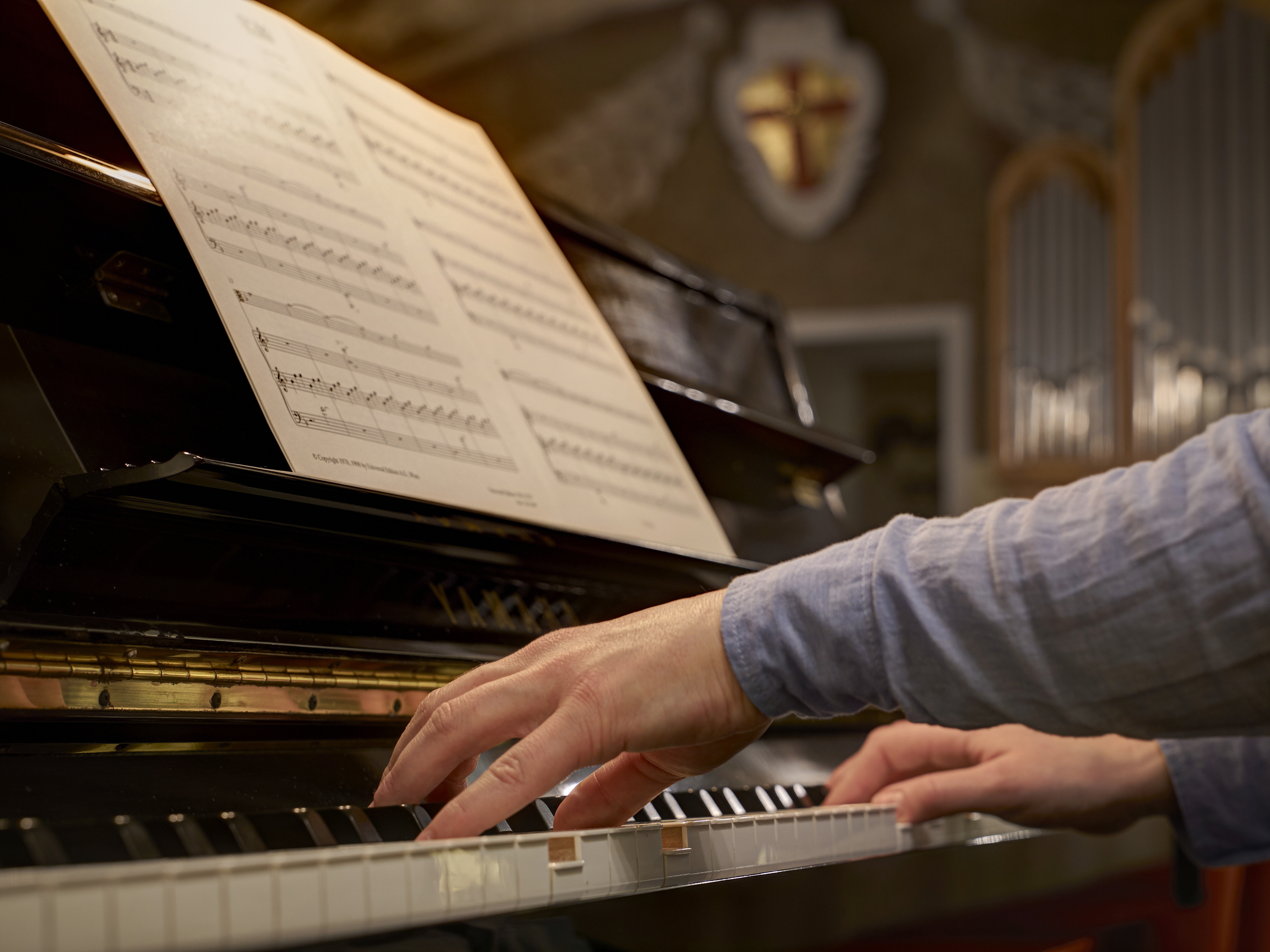 Tangenterna på ett piano trakteras av en musiker händer. 