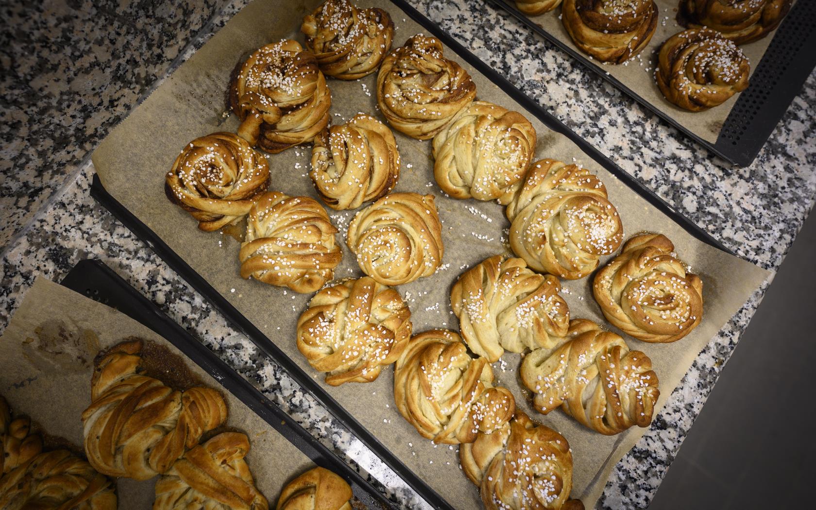 Plåtar med nygräddade kanelbullar.