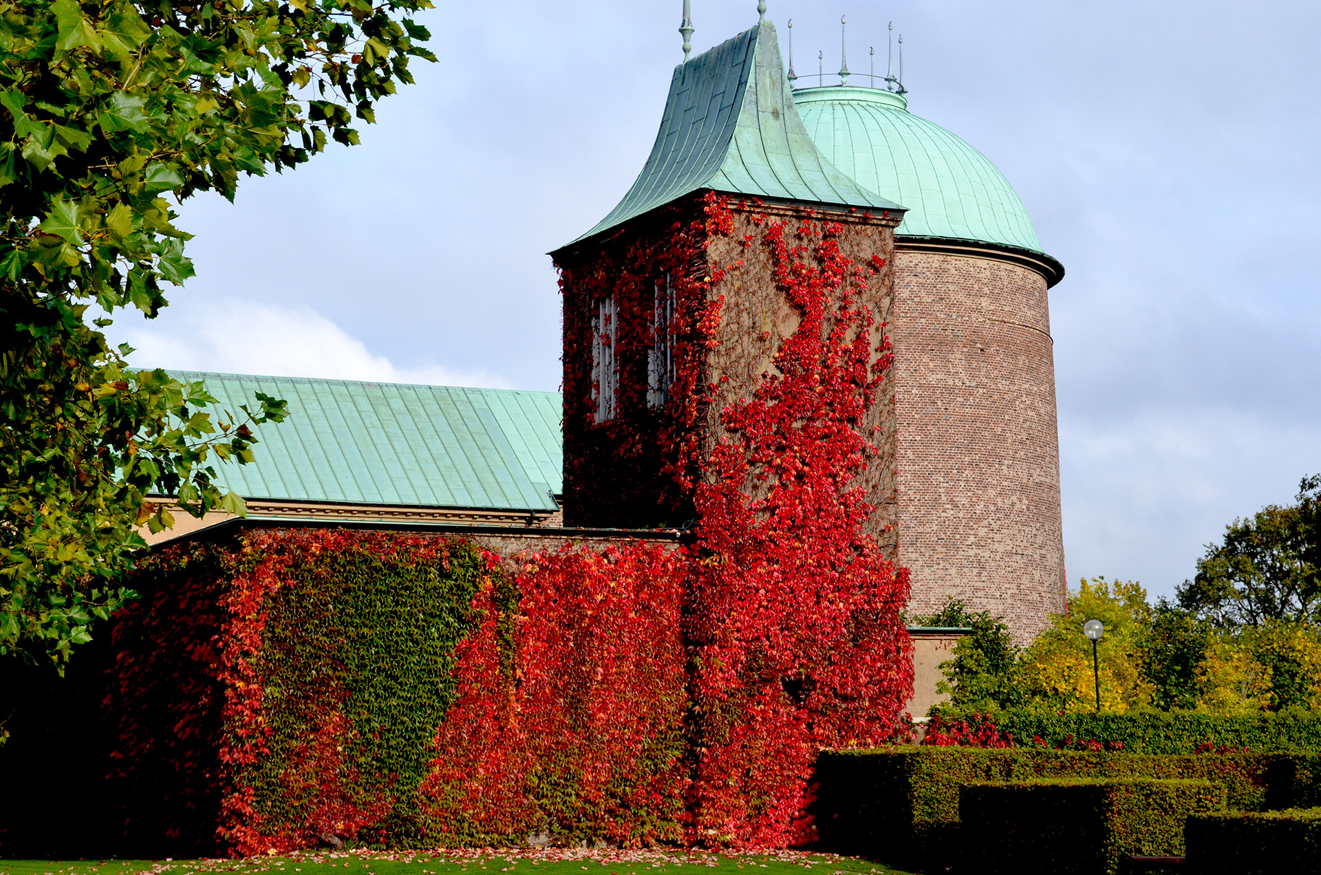 Krematoriet i Helsingborg. Byggnader i rött tegel och koppartaket. En vägg är helt klätt med vildvin.