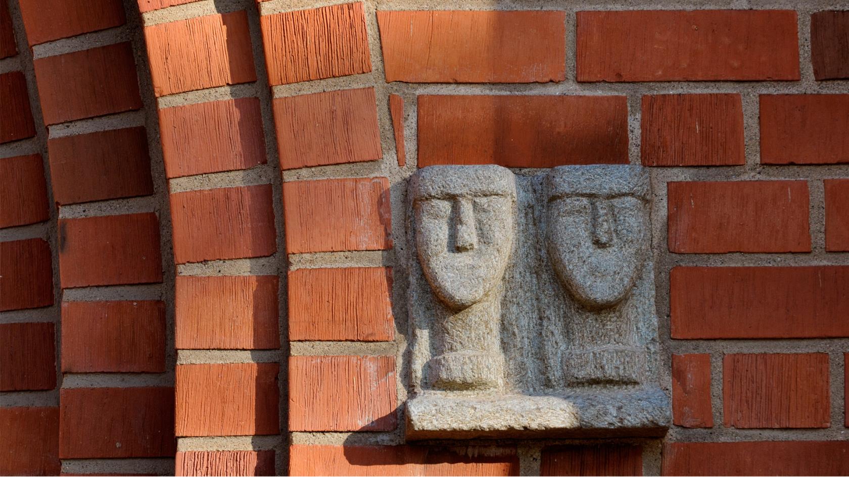 Skulptur av två huvuden i sten på Växjö domkyrkas fasad.