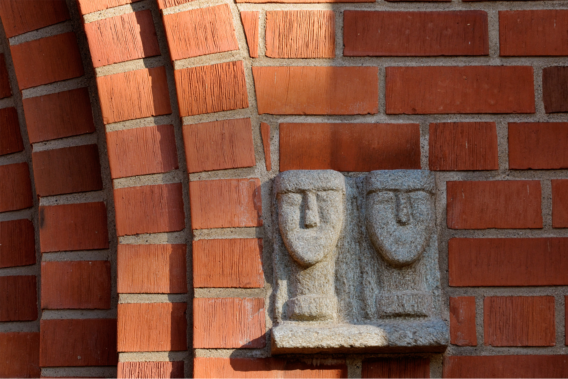 Skulptur av två huvuden i sten på Växjö domkyrkas fasad.