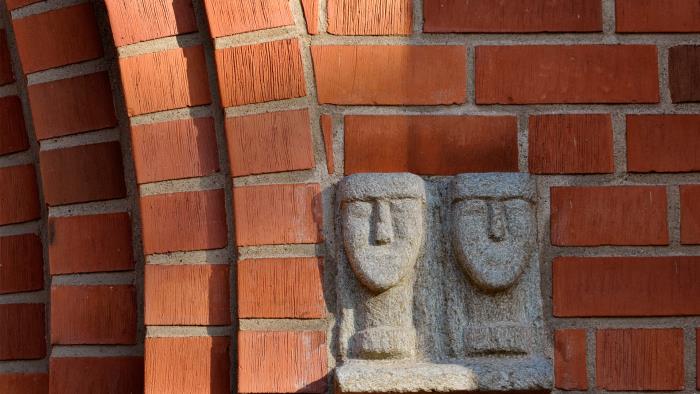 Skulptur av två huvuden i sten på Växjö domkyrkas fasad.