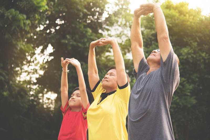 Qigong och meditation, tre personer som stretchar armarna uppåt.