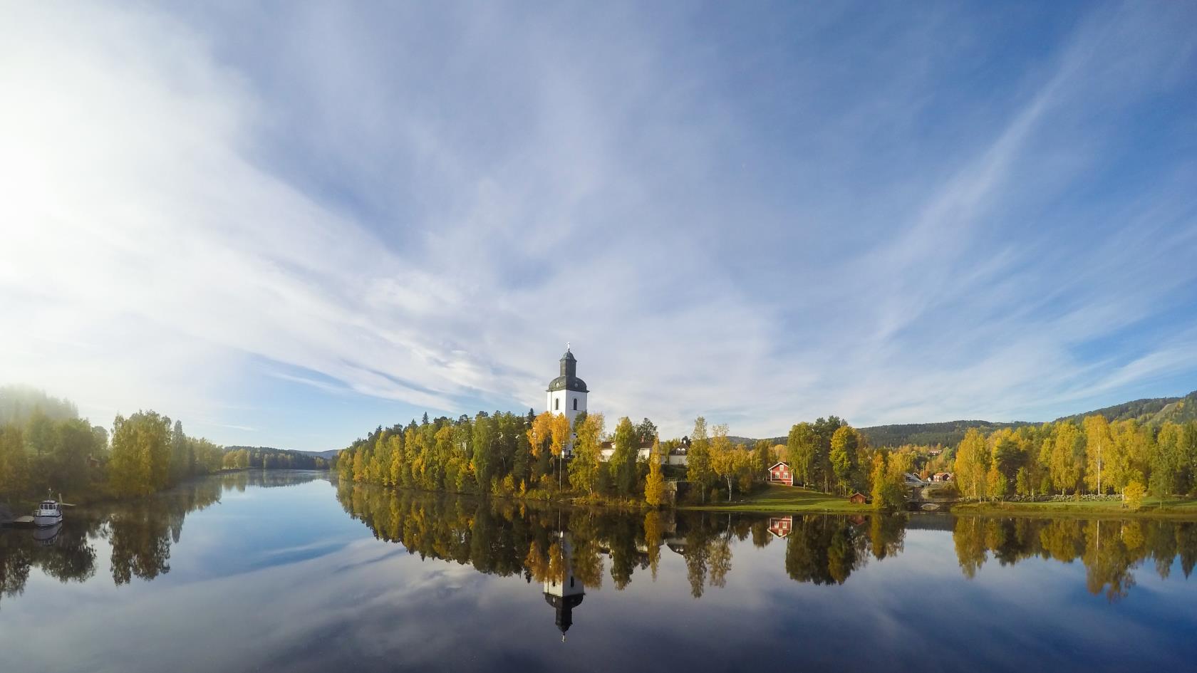 En kyrka vid vattnet reflekteras i den stilla vattenytan.